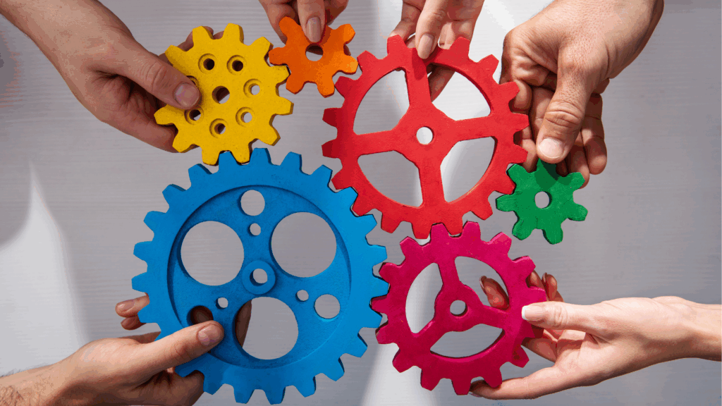 Hands connecting colorful gears symbolizing teamwork